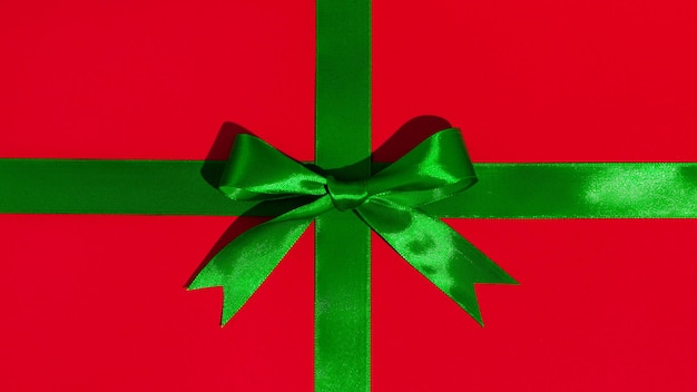 Groen cadeaulint en strik op rode papieren achtergrond
