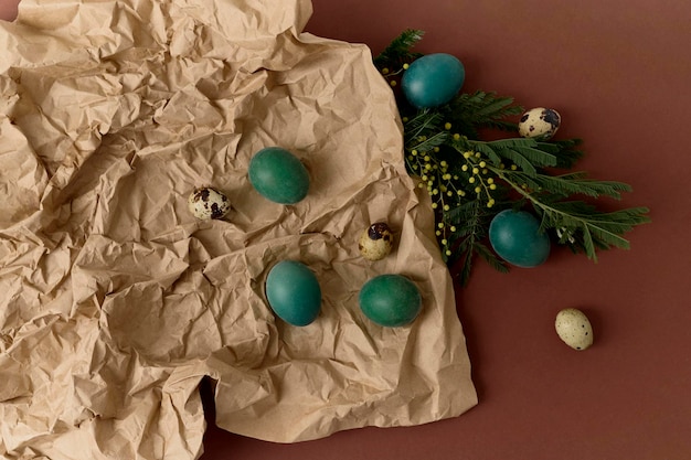 Groen gekleurde eieren op een kraftpapier met groene takken op een bruine achtergrond