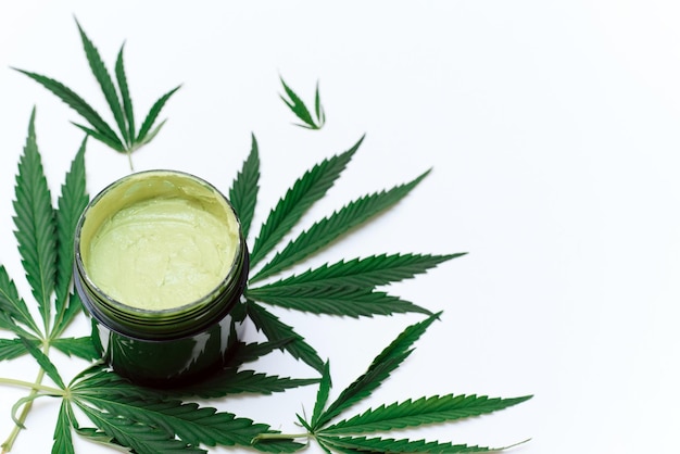 Groen kleimasker met hennepextract op een witte achtergrond met kopieerruimtegebruik van cannabis bij het maken van cosmetica