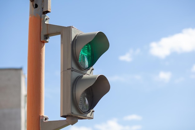 Groen licht op een voetgangersverkeerslicht tegen een blauwe lucht Veilige oversteek van de weg voetgangers