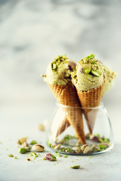 Groen roomijs in wafelkegel met chocolade en pistachenoten op grijze steen. Zomer eten concept, kopie ruimte. Gezond glutenvrij ijs.