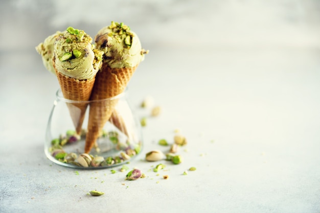 Foto groen roomijs in wafelkegel met chocolade en pistachenoten op grijze steen. zomer eten concept, kopie ruimte. gezond glutenvrij ijs.