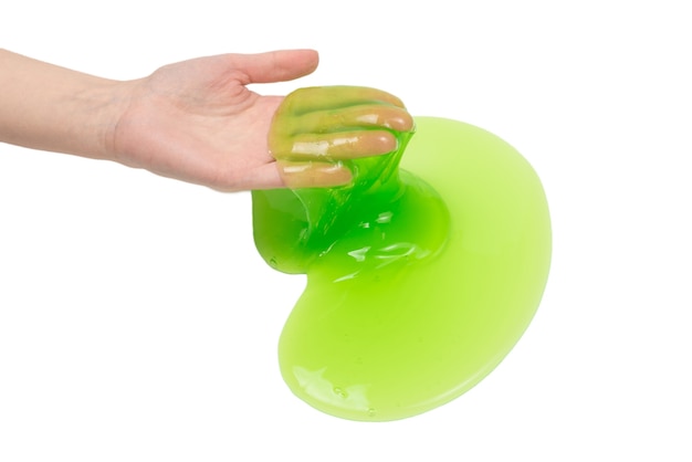 Groen slijmstuk speelgoed in vrouwenhand die op witte achtergrond wordt geïsoleerd.