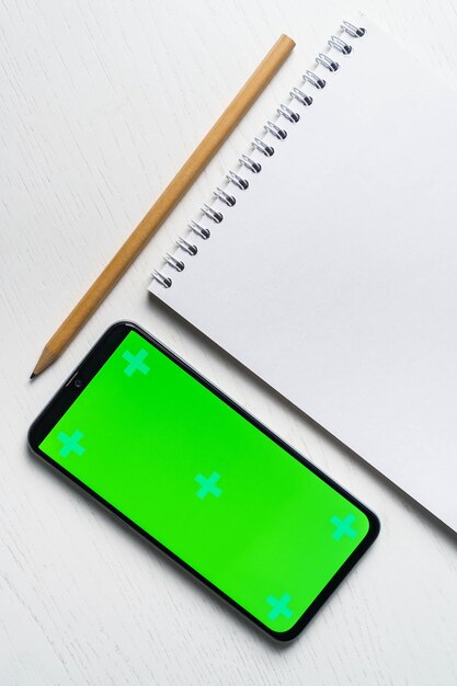 Groen verlof met blanco notitieblok smartphone groen scherm mockup en potlood plat leggen Bovenaanzicht