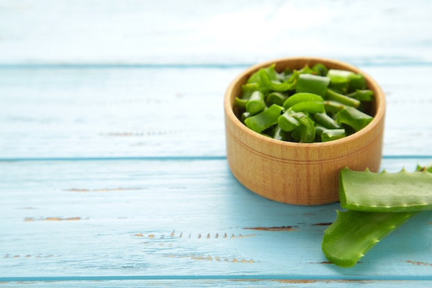 Groen vers aloë verablad in houten kom op blauwe achtergrond. natuurlijke kruiden medische plant, huidverzorging, gezondheid en beauty spa concept. bovenaanzicht