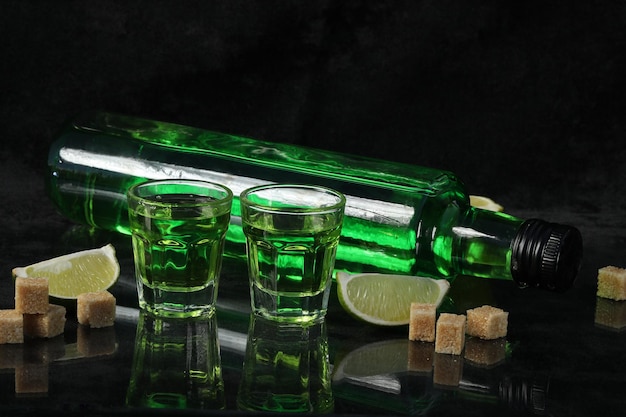 groene absintdrank op de zwarte achtergrond met suiker en limoen