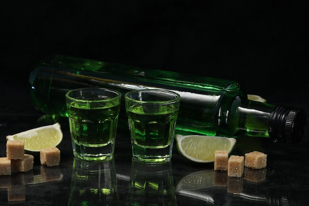 groene absintdrank op de zwarte achtergrond met suiker en limoen