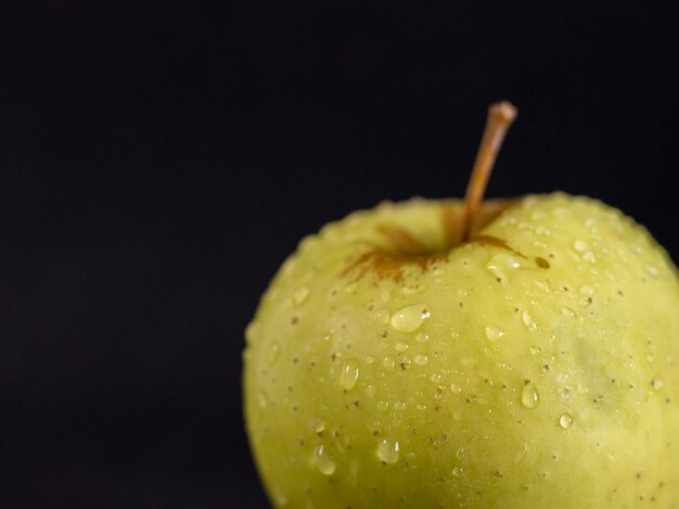 Groene appel met druppels op zwarte achtergrond