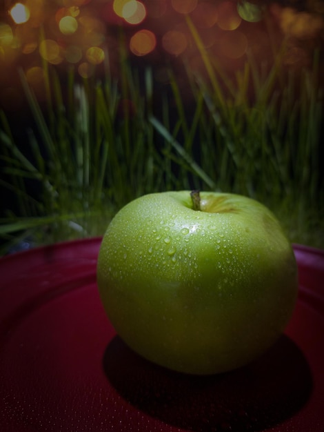 Groene appel op een stijlvolle rode plaat op een donkere achtergrond