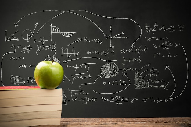 Groene appel op stapels boeken op bureau voor terug naar schoolconcept