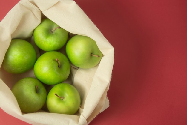 Groene appels in bolsazak over rode achtergrond. Geen afvalconcept.