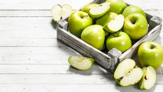 Groene appels in een kleine doos. op een witte houten achtergrond.