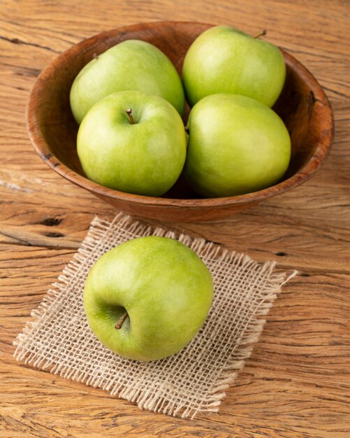 Groene appels in een kom over houten tafel.