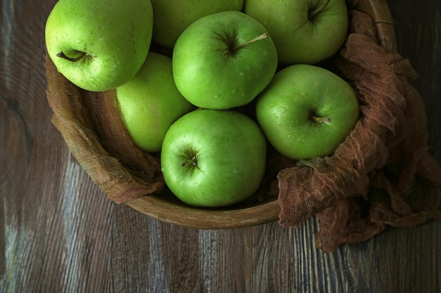 Groene appels in kom met stof op houten tafelblad bekijken