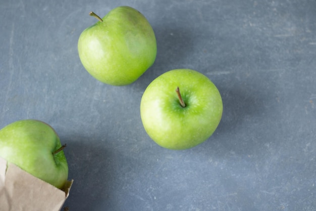 groene appels op een grijze achtergrond met ruimte voor tekst Drie groene appels op betonnen pagina