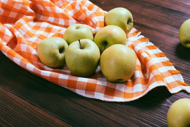 Groene appels op een houten tafel en oranje geruit tafellaken