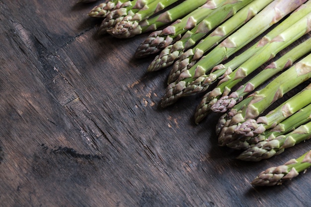 Groene asperge. Bossen van groene asperges op een donkere houten rustieke achtergrond