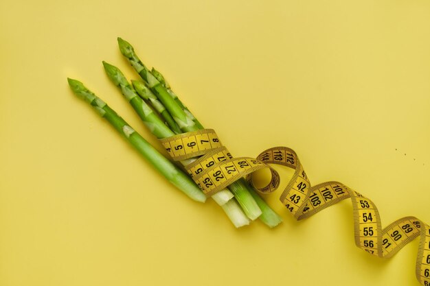 Foto groene asperges en meetband geïsoleerd op geel
