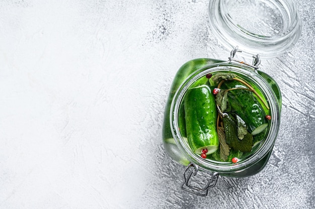 Groene augurk komkommers in een glazen pot. Natuurlijk product. Witte achtergrond. Bovenaanzicht.