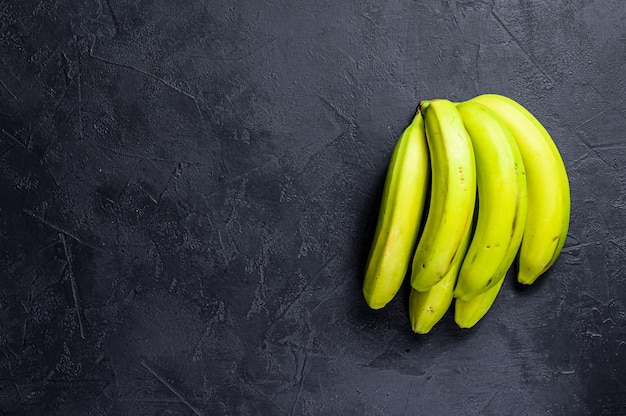 Groene bananen. Zwarte achtergrond. Bovenaanzicht. Ruimte voor tekst