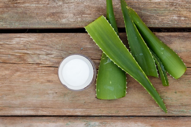 Groene bladeren van aloë vera plant en vochtinbrengende crème op rustieke houten achtergrond