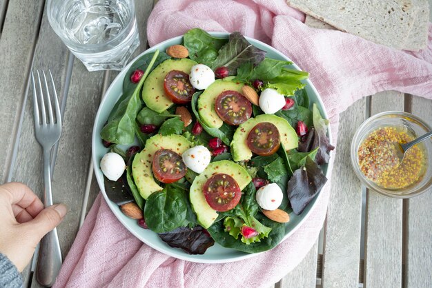 Groene bladsalade met avocado-granaatappel-mozzarellabolletjes, cherrytomaatjes en amandelen