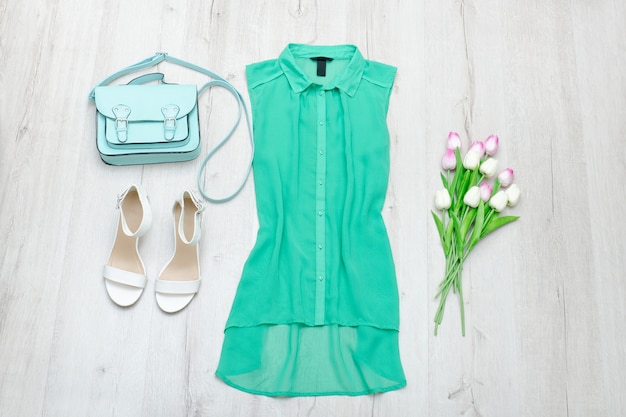 Groene blouse, witte schoenen, mint tas en een boeket tulpen. Houten achtergrond