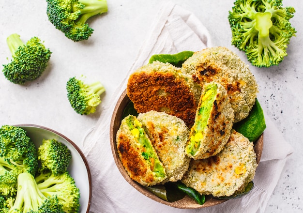 Groene broccoliburgers in kokosnotenshell schotel op witte achtergrond, hoogste mening.