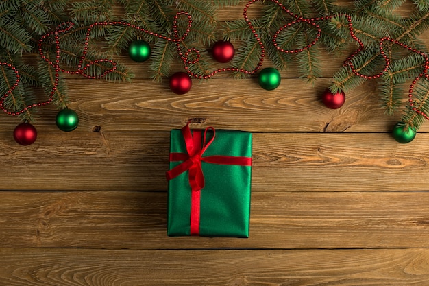 Groene cadeau met rood lint, kerstboom en decoraties op de tafel