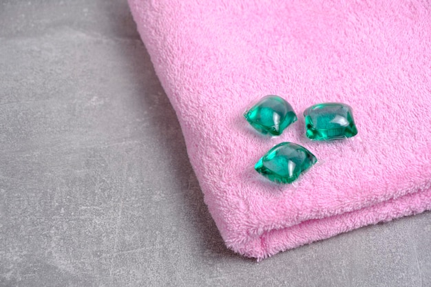 Groene capsules voor het wassen van kleding op badstof roze schone handdoek op concrete achtergrond