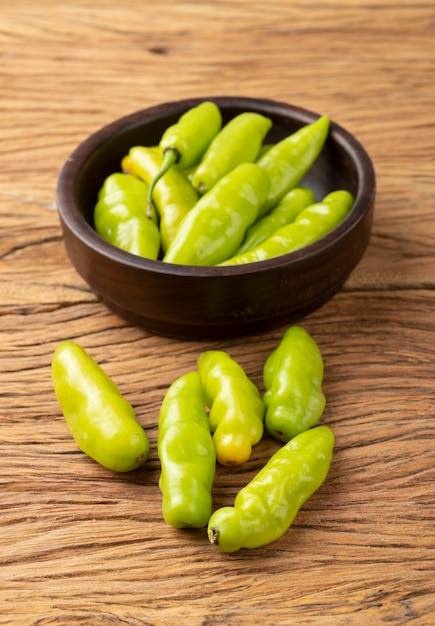 Groene cheiro (geur / geur) peper op een kom over houten lijst.