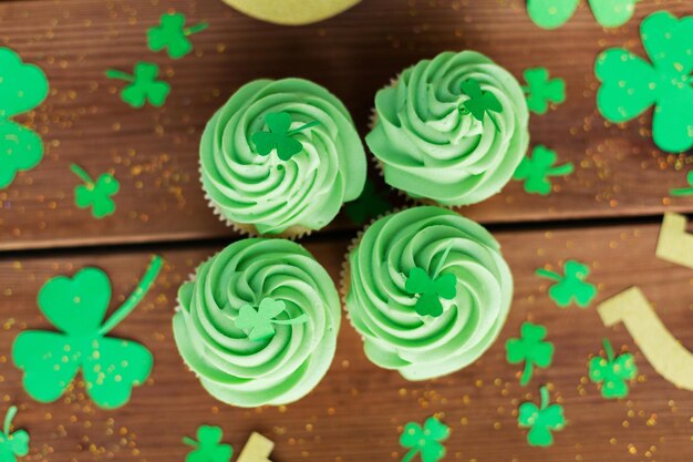 Groene cupcakes en shamrock op een houten tafel.