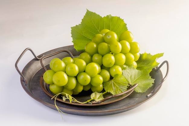 Groene druiven in een dienblad op een witte achtergrond