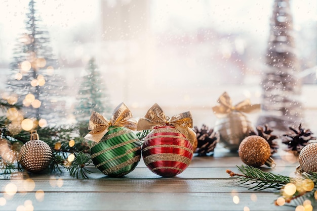 Groene en rode kerstbollen met gouden bogen, sparren takken en ornamenten op houten achtergrond met kerstverlichting bokeh, Merry Christmas wenskaart met kopie ruimte