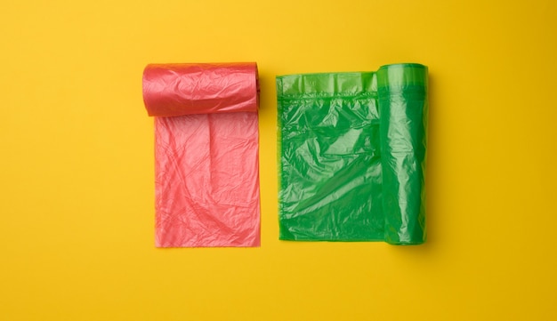 Groene en rode plastic zakken voor vuilnisbak op gele achtergrond, bovenaanzicht