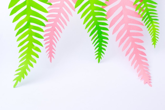 Groene en roze tropische papier palmbladeren op wit oppervlak