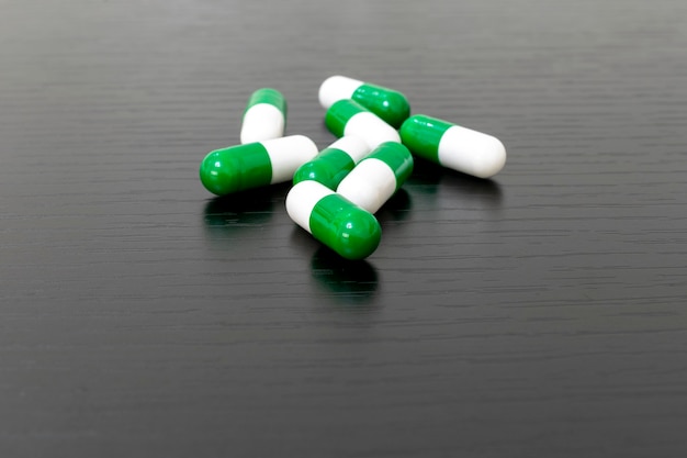 Groene en witte medicijncapsules op zwarte achtergrond