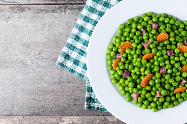 Groene erwten met serrano ham en wortel op een houten tafel