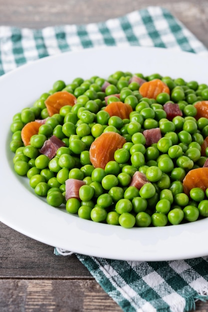 Groene erwten met serranoham en wortel op houten tafel