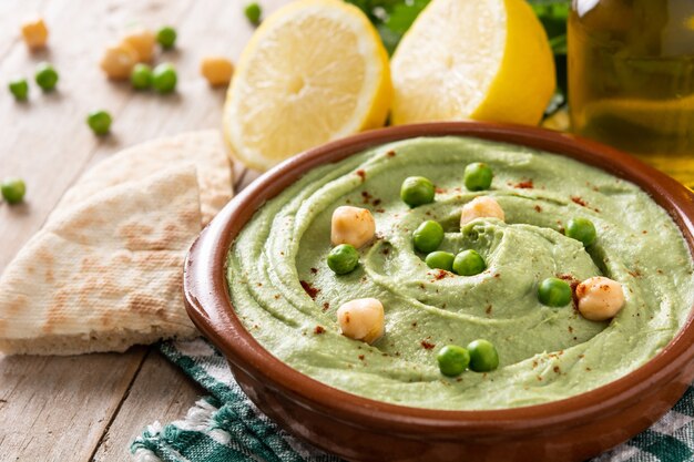 Groene erwtenhummus en pitabroodje op houten tafel