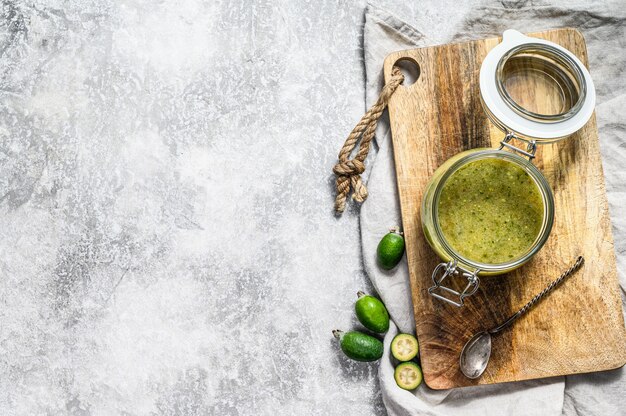 Groene feijoa-jam op een houten snijplank in een glazen pot.