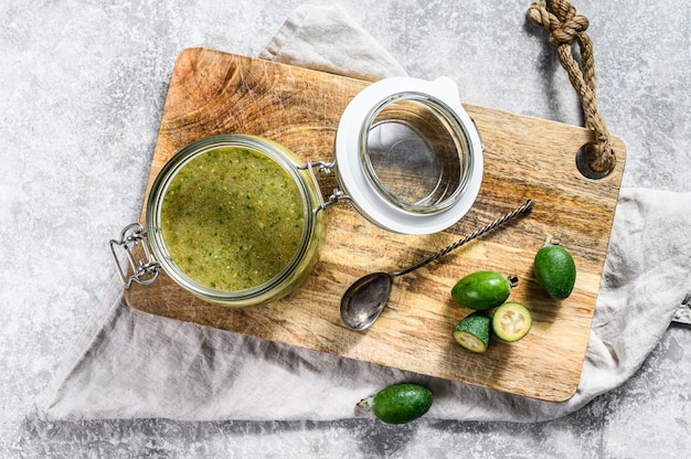 Groene feijoa-jam op een houten snijplank in een glazen pot.