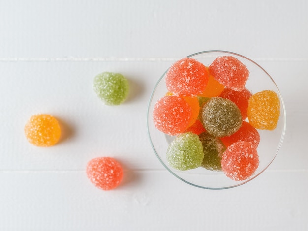 Groene, gele en rode marmelade in een glazen kom op een witte tafel. Heerlijke snoepjes gemaakt van gelei met suiker. Het uitzicht vanaf de top.