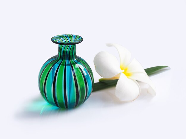 Groene glasvaas met witte plumeria spa bloembloei en geïsoleerde bladeren.