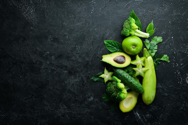 Groene groenten en fruit gezonde voeding op zwarte stenen achtergrond tropisch fruit bovenaanzicht vrije ruimte voor uw tekst