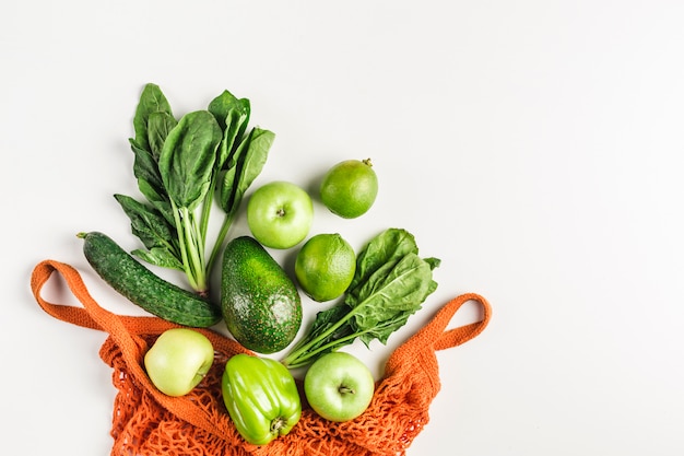 Groene groenten en fruit in oranje touwzak