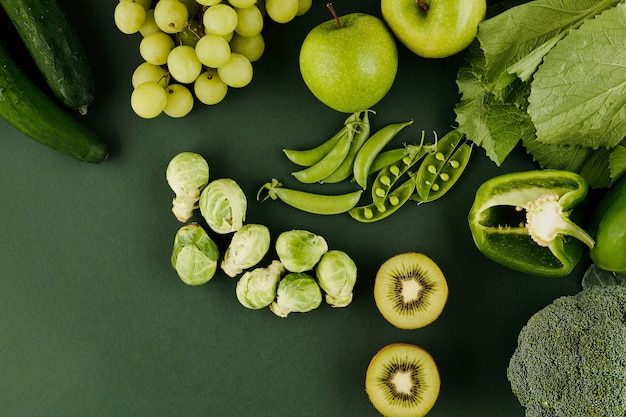 Groene groenten en fruit op tafel zoals kiwi, appels, erwten, druiven, peper en spruitjes