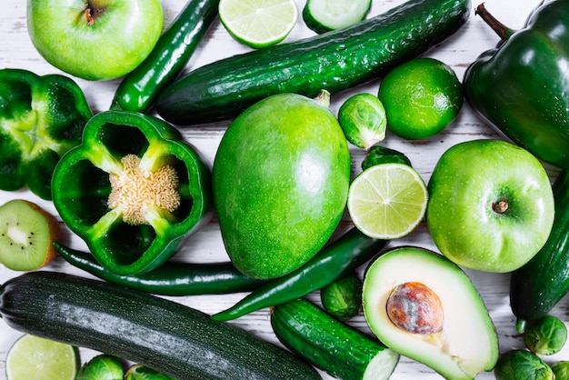 Groene groenten en fruit op witte houten achtergrond gesneden voor halve dia's bovenaanzicht