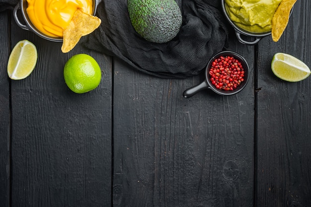 Groene guacamole en gele kaas dipsaus voor traditionele Mexicaanse taco's, op zwarte houten tafel, bovenaanzicht of plat