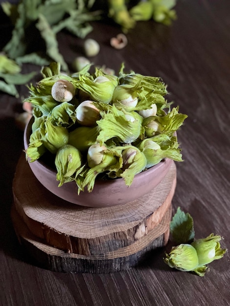 groene hazelnoten in een houten kom op houten zaagsneden, onrijpe hazelnoten op een donkere achtergrond